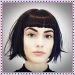 Close-up of a woman with a chic micro bob haircut and blunt bangs, showcasing a trendy and stylish look